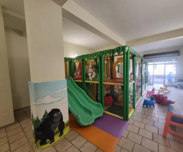 Scivolo doppio verde e colonna decorata con gorilla nella sala feste per bambini a Letojanni.